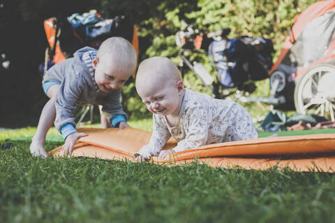 Baby-Mädchen und Kleinkind-Junge mit Isomatte im Gras, lizenzfreies Stockfoto