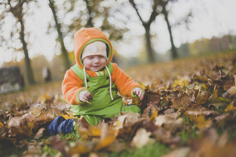 Glückliches kleines Mädchen spielt im Herbstlaub, lizenzfreies Stockfoto