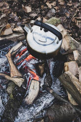 High angle close up of metal kettle hanging over a campfire. - MINF11432