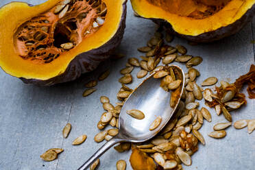 High angle close up of silver tablespoon and purple pumpkin with orange flesh cut in half. - MINF11513