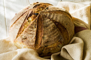 Nahaufnahme eines frisch gebackenen runden Brotlaibs auf einem Geschirrtuch. - MINF11541