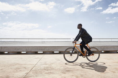 Man riding bike on waterfront promenade - JND00043
