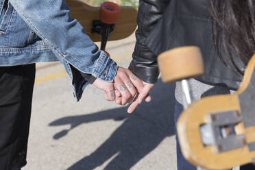 Tätowierter junger Mann hält Hand mit seiner Freundin, Teilansicht - JPTF00133