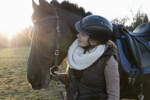 Smiling woman with horse at backlight - CRF02856