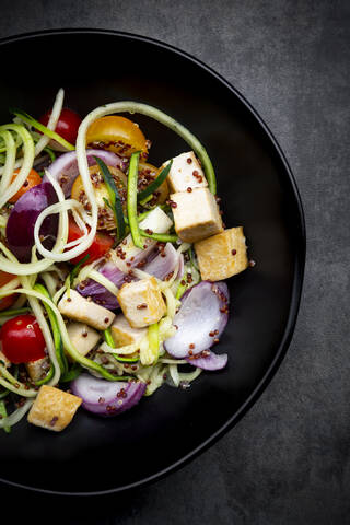 Zucchini-Zoodles mit gebratenem Tofu, rotem Quinoa, Zwiebeln und Tomaten, lizenzfreies Stockfoto