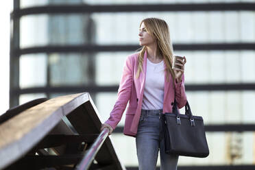 Young businesswoman using smartphone and holding coffee to go - JSRF00192