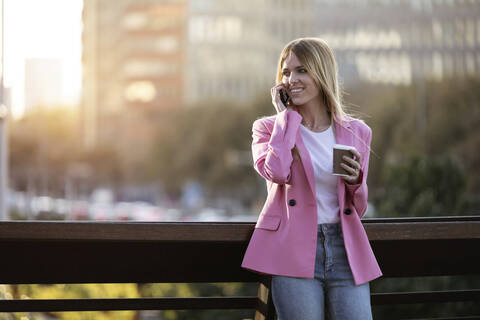Junge Geschäftsfrau mit Smartphone und Coffee to go in der Hand, lizenzfreies Stockfoto