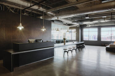 Stools at bar by reception desk in office - MINF12065