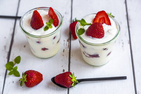 Joghurt mit frischen Erdbeeren und Minze auf Holz, lizenzfreies Stockfoto