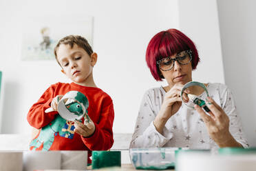 Mutter und Sohn basteln zu Hause und bemalen Papprollen, um einen Weihnachtsbaum zu gestalten - JRFF03240