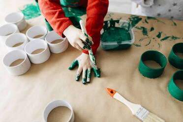 Kind malt seine Hände mit einem Pinsel grün an - JRFF03249