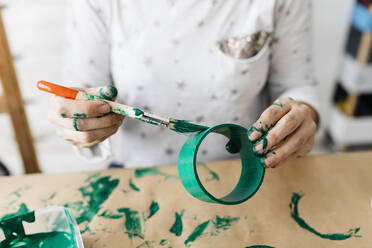 Frauenhände bemalen eine Papprolle mit einem grünen Pinsel - JRFF03250