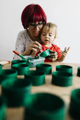 Mutter und Tochter basteln zu Hause und bemalen Papprollen, um einen Weihnachtsbaum zu gestalten - JRFF03256