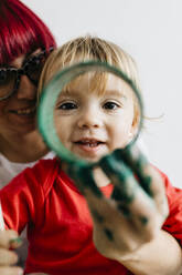 Porträt eines lächelnden Kindes mit seiner Mutter durch eine Papprolle - JRFF03258