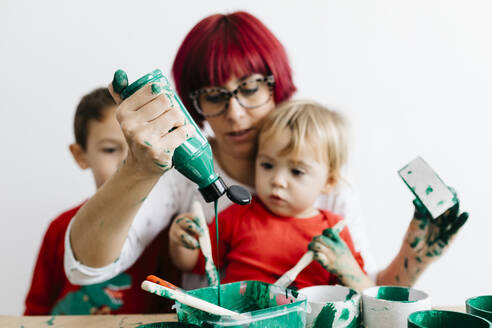 Mutter mit ihren Kindern beim Basteln zu Hause und Malen mit Grün - JRFF03261