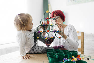Mutter und Tochter basteln zu Hause mit Zubehör für einen Weihnachtsbaum - JRFF03268