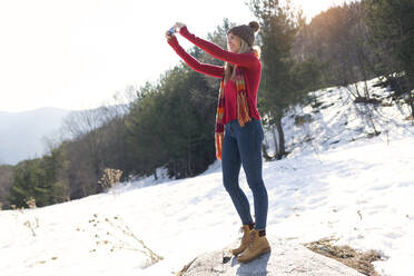 Young blond woman taking a selfie in winter - JSRF00223