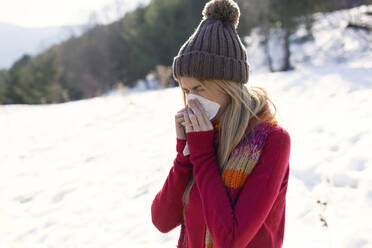 Young blond woman blowing nose in winter - JSRF00224