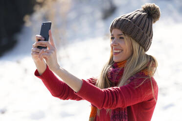 Young blond woman taking a selfie in winter - JSRF00228