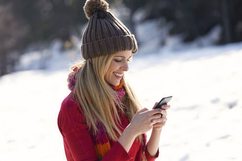 Young blond woman using smartphone in winter - JSRF00229