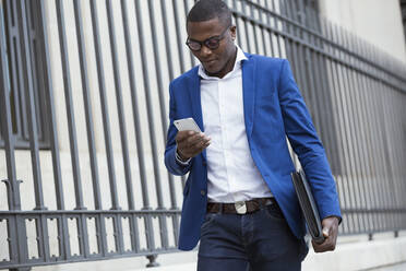 Junger Geschäftsmann in blauer Anzugsjacke und mit Smartphone - JSRF00244