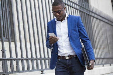 Young businessman wearing blue suit jacket and using smartphone - JSRF00244