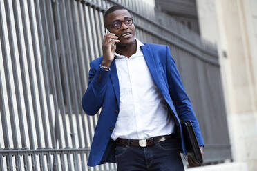 Young businessman wearing blue suit jacket and using smartphone - JSRF00245