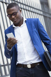 Junger Geschäftsmann in blauer Anzugsjacke und mit Smartphone - JSRF00246