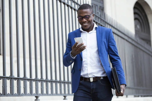 Young businessman wearing blue suit jacket and using smartphone - JSRF00249