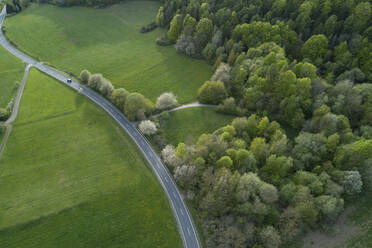 Abstrakte Luftaufnahme einer Landstraße durch eine Landschaft mit landwirtschaftlichen Feldern, Wiesen und Wald, Frühling, Franken, Bayern, Deutschland - RUEF02245