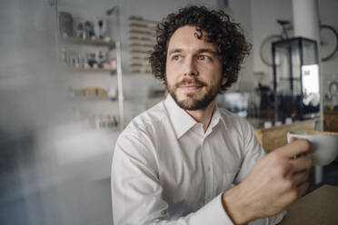 Businessman drinking coffee in a coffee shop - KNSF05970