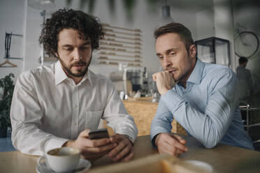 Two businessmen having a meeting in a coffee shop - KNSF05973