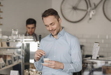 Businessman drinking fresh coffee in a coffee shop, smiling - KNSF05980