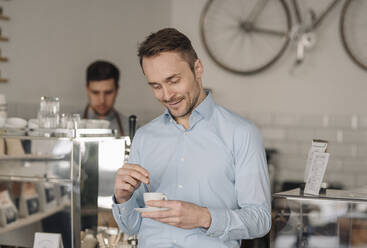 Geschäftsmann trinkt frischen Kaffee in einem Café, lächelnd - KNSF05980