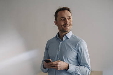 Smiling businessman using smartphone - KNSF05999