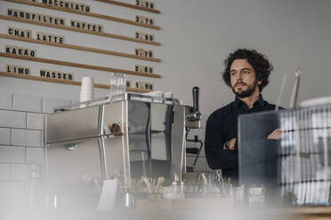 Proud coffee shop owner standing behind counter - KNSF06023