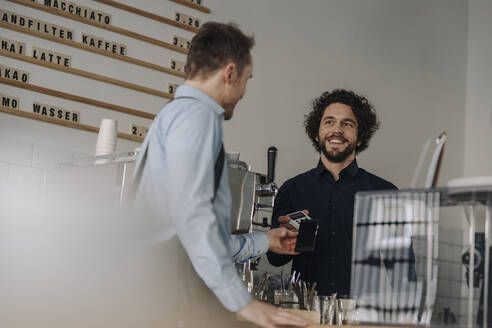 Kunde zahlt kontaktlos in einem Coffee Shop - KNSF06024