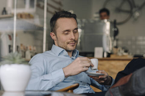 Erfolgreicher Geschäftsmann sitzt in einem Café und trinkt Kaffee, lizenzfreies Stockfoto