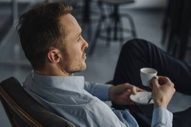 Successful businessman sitting in coffee shop - KNSF06026