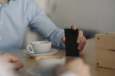 Two businessmen having a meeting, close up of hand, holding smartphone - KNSF06041