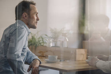 Successful businessman sitting in coffee shop, having a meeting - KNSF06046