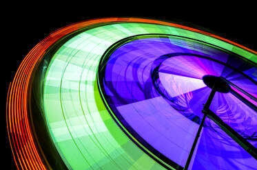 Sich drehendes Neon-Riesenrad in einem nächtlichen Vergnügungspark - MINF12296