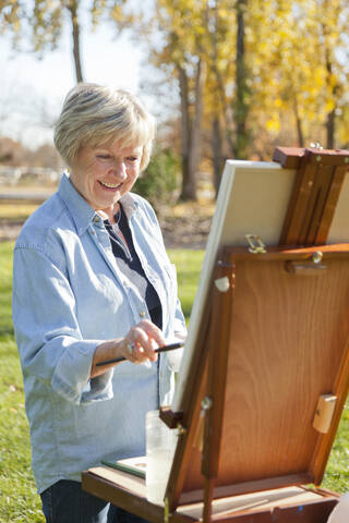Ältere Frau malt im Freien, lizenzfreies Stockfoto