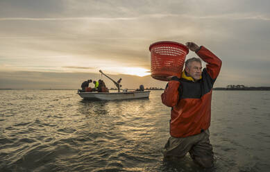 Kaukasischer Fischer trägt Korb im Wasser - BLEF06712