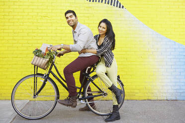 Indian couple riding bicycle on city street - BLEF06741