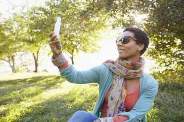 Schwarze Frau benutzt Mobiltelefon im Park - BLEF06752