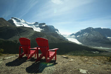 Red lawn chairs overlooking scenic mountain landscape - MINF12308