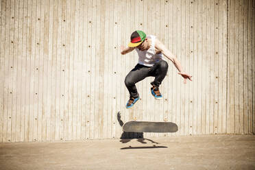 Kaukasischer Mann macht Skatetrick in der Nähe einer Holzwand - MINF12327