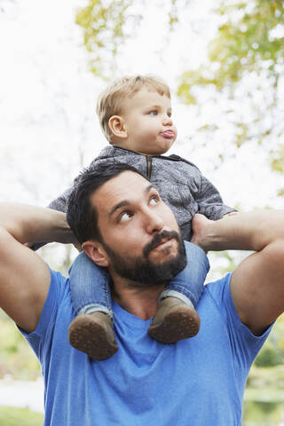 Kaukasischer Vater trägt seinen kleinen Sohn im Freien, lizenzfreies Stockfoto