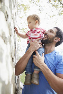 Caucasian father holding baby son under tree - BLEF06859